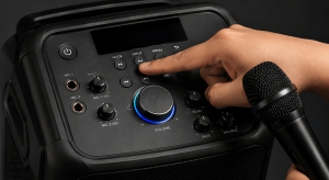 Kamay na sumusuri sa mga button, volume knob, at microphone controls ng karaoke machine.